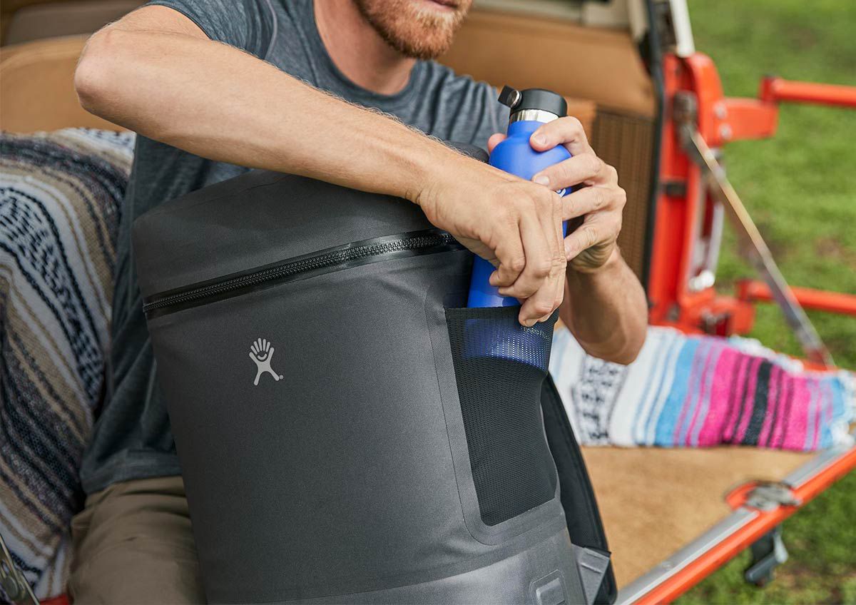A man putting a Hydro Flask bottle into a Hydro Flask Unbound Series Soft Cooler Pack. 