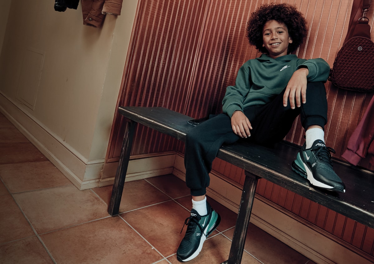 Boy in a mudroom wearing Nike.