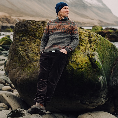 A man leaning on a bolder near the sea.