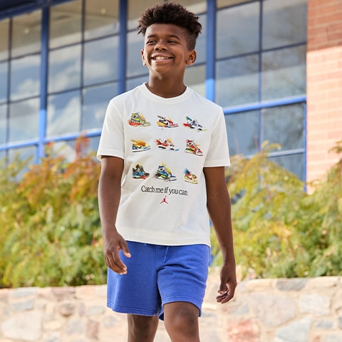 A boy walking in a tee ans shorts.