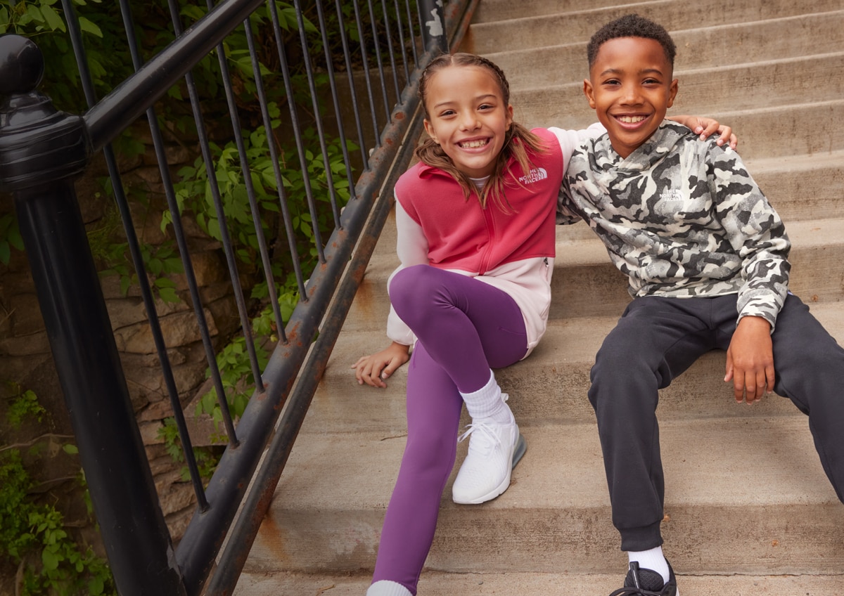 Two kids sitting on steps outside.