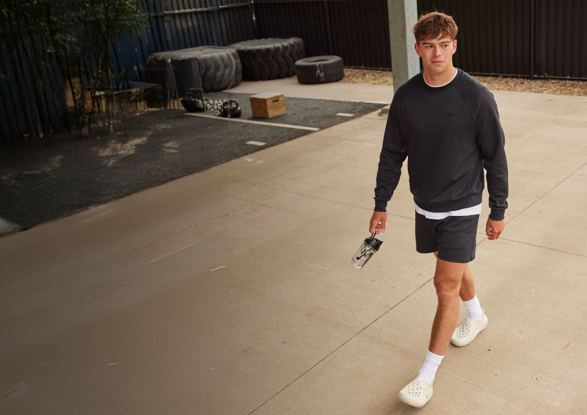a man walking in a hoodie and shorts