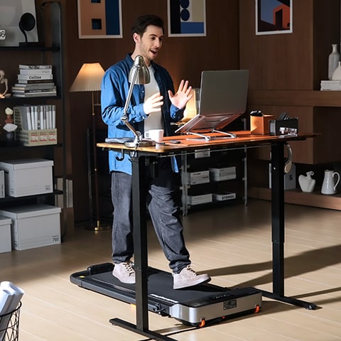 A man using a compact treadmill at a standing desk