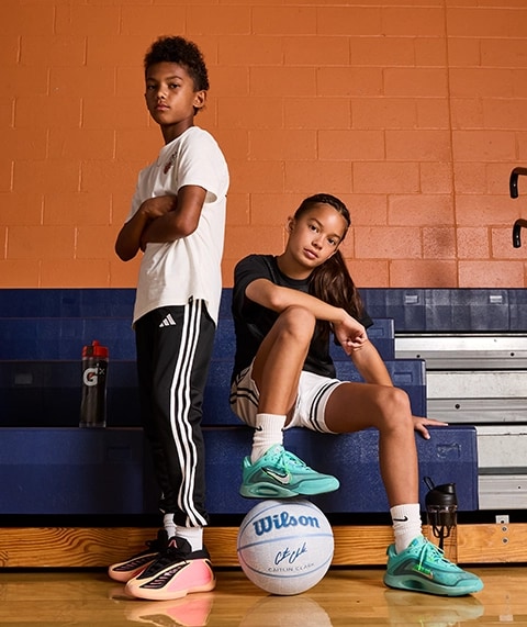 Two kids in the bleachers getting ready for basketball.