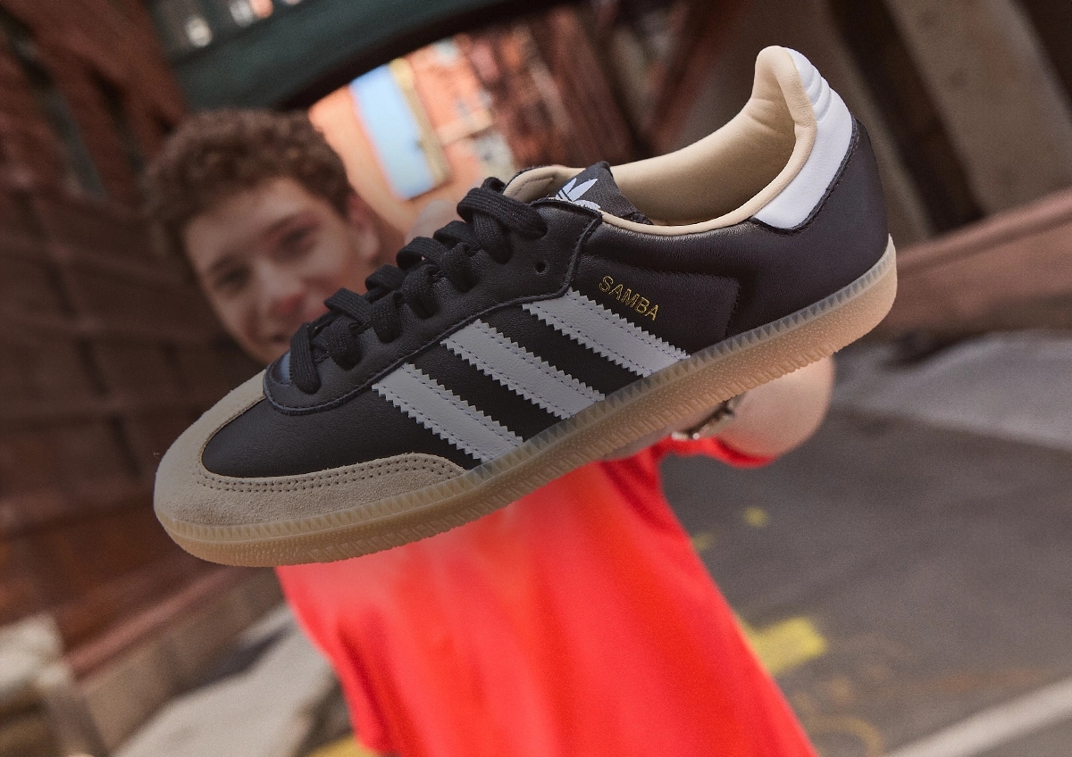 Man holding up an adidas samba shoe.