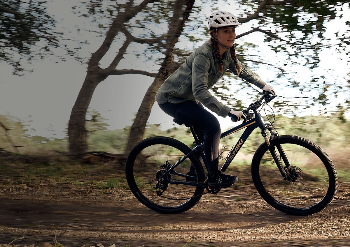 Woman on bike riding on a trail.