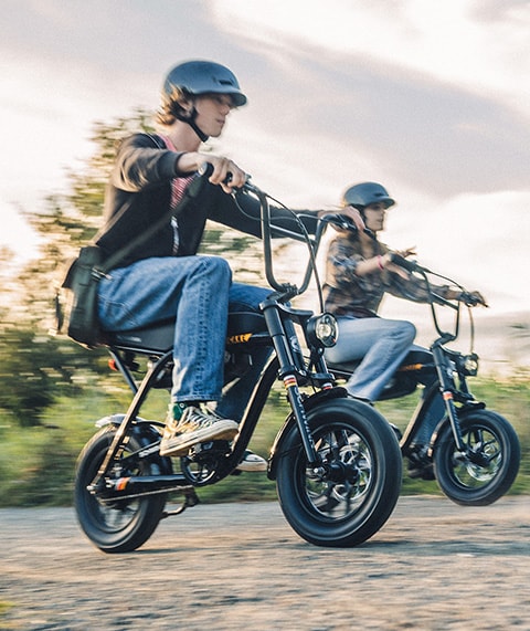 Two people riding ebikes along a path