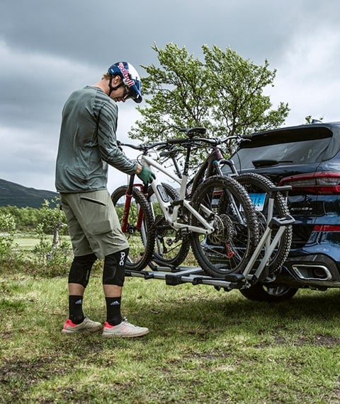 Man securing bikes to car.