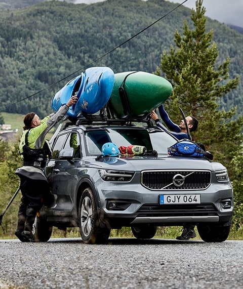 Couple securing kayaks to car.