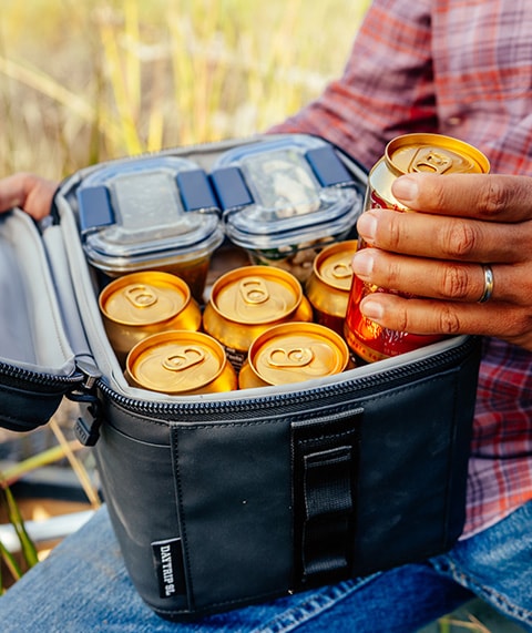 Man grabbing a cold can from a small cooler.