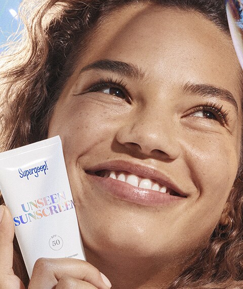 Woman holding Supergoop! Unseen Sunscreen.