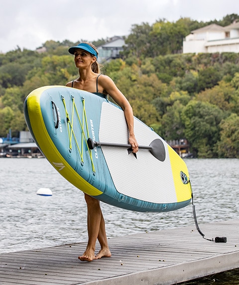 Woman holding stand up paddle board.