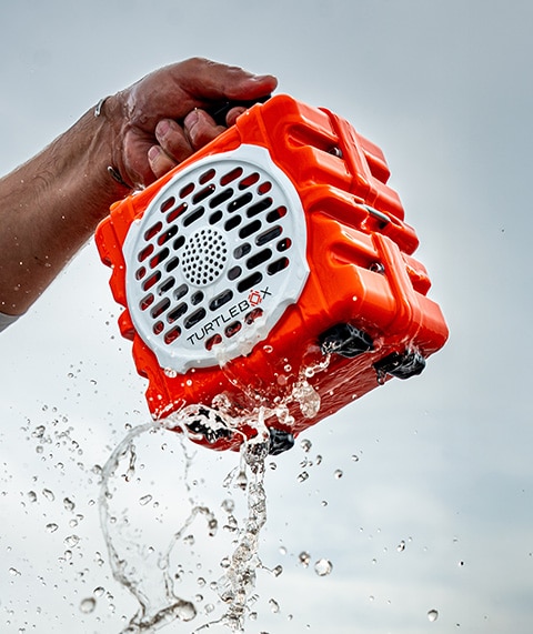 Hand holding orange Turtlebox speaker.