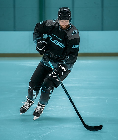 Hockey player in a dark uniform on ice.