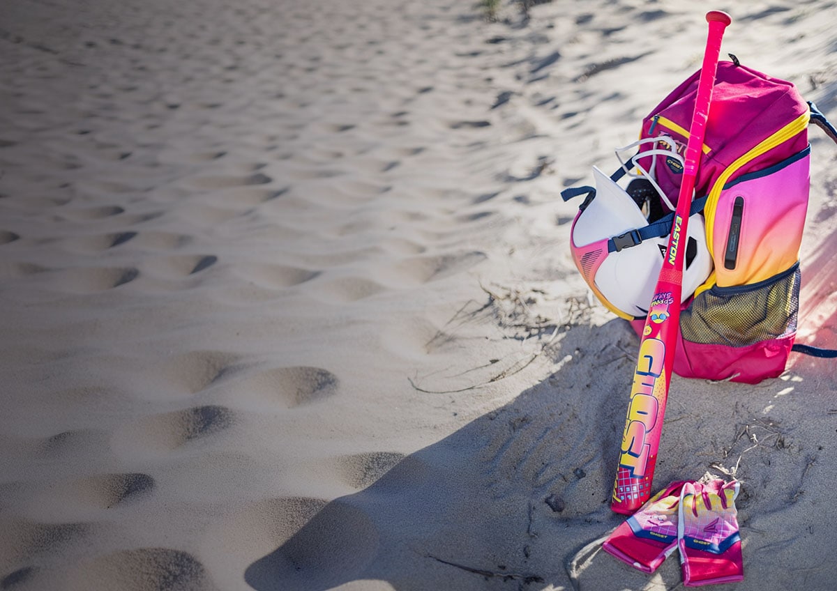 Softball equipment on beach sand.