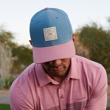 An image of a golfer wearing a TravisMathew hat.
