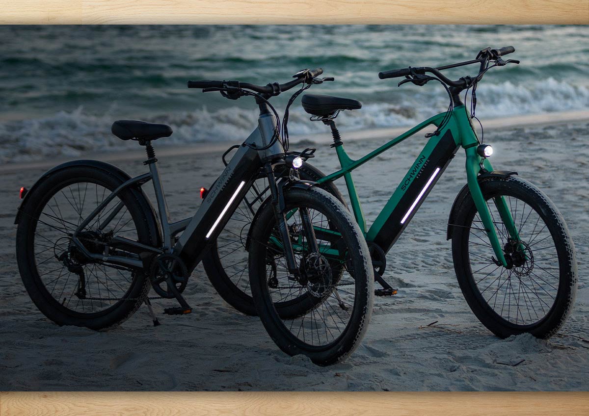Schwinn e-bikes on a beach along the shoreline.
