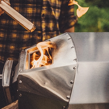 A man loading wood into an Ooni pizza oven.
