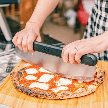 A woman cutting a pizza.