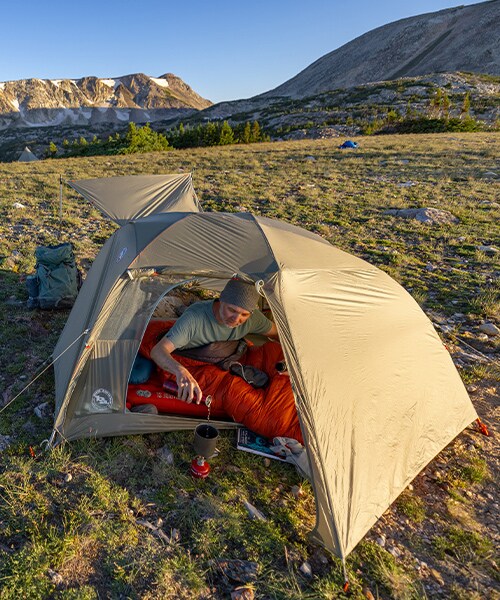 A camper in the mountains next to his Big Agnes tent.