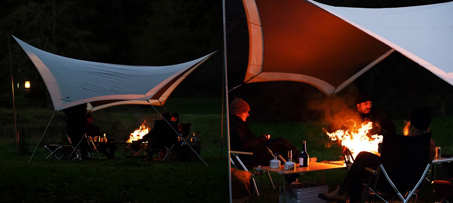 Campers sitting at a campfire near a Snow Peak awning.
