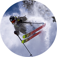 A skier kicking up powder descending a mountain.