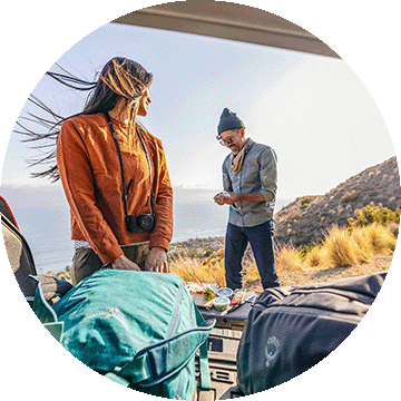Two people unloading hiking equipment from a vehicle