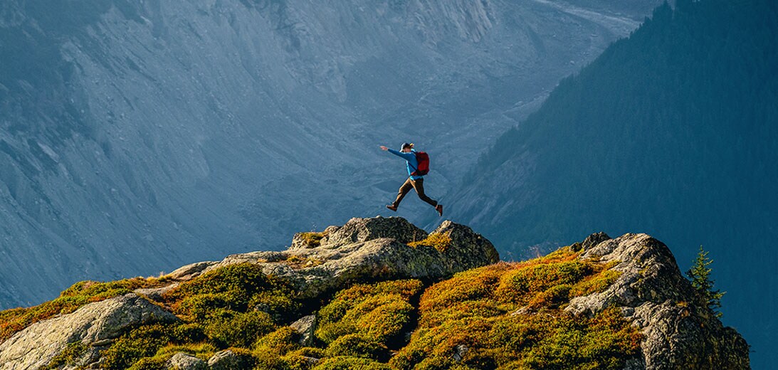 A hiker jumping along a cliff edge