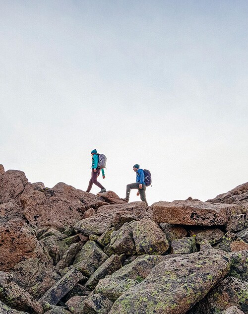 Two hikers walking amongst large boulders