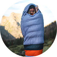 A woman standing while bundled in a sleeping bag.