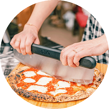 A woman cutting a pizza.