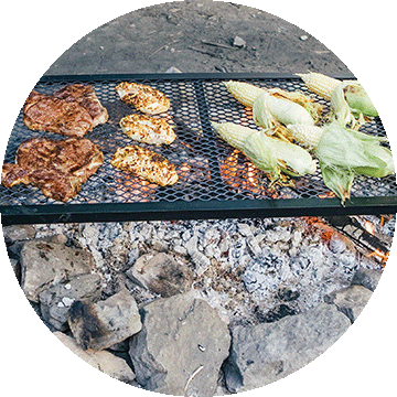 Meats and earns of corn cooking over an open flame.