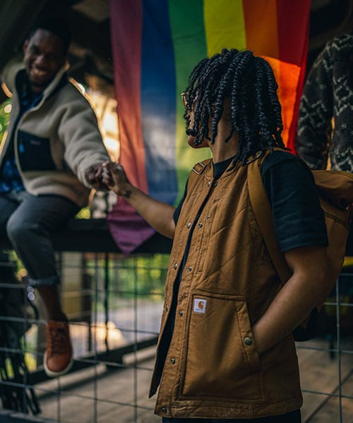 people socializing in front of PRIDE flag