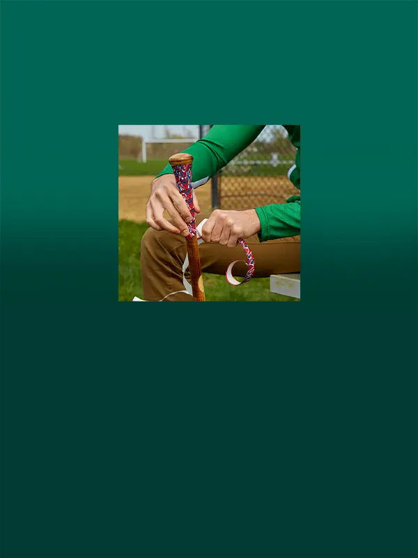 Image features a teammate wrapping a grip on a bat.
