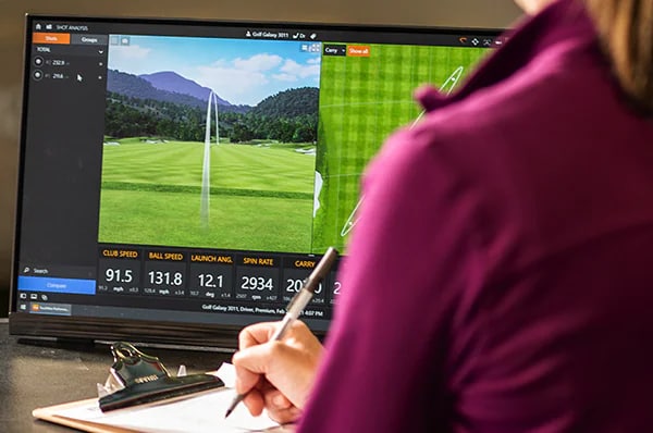 A Golf Pro Reviewing Data On A Launch Monitor