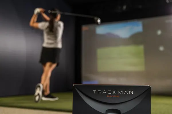 A Female Golfer Swinging A Club In A Hitting Bay